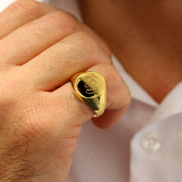 man wearing gold signet ring with engraving