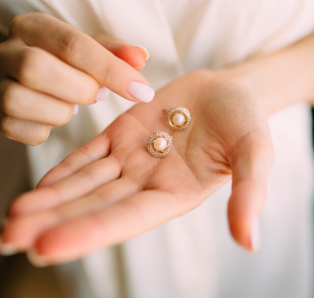 woman holding pair of earrings