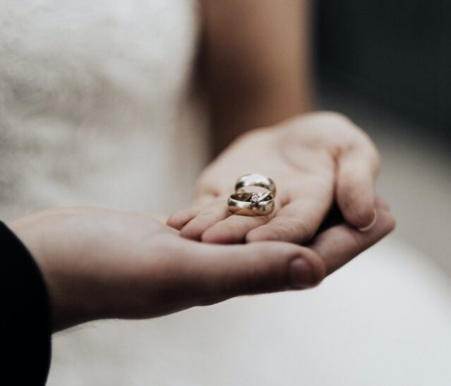 man and woman holding wedding and engagement rings
