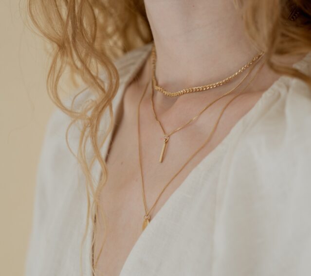 woman wearing gold layered necklaces
