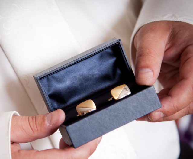 man holding gold cufflinks in gift box