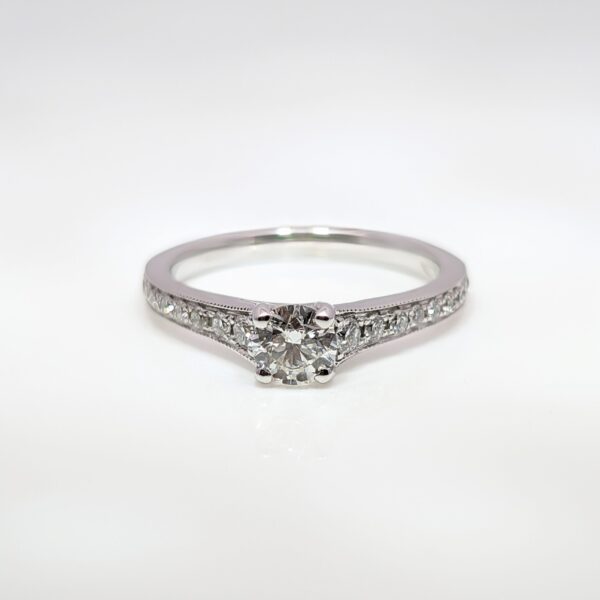 This 18ct white gold diamond engagement ring has an elegant milgrain edge encasing the shoulder stones, and a high-set centre stone making it ideal for your future wedding band.