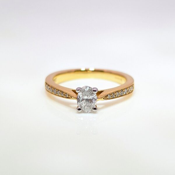 Discover our 4 Claw Oval in 18ct Yellow Gold, with a Centre Stone and Pavé set Diamond Shoulders. Oval Diamond Engagement Ring.