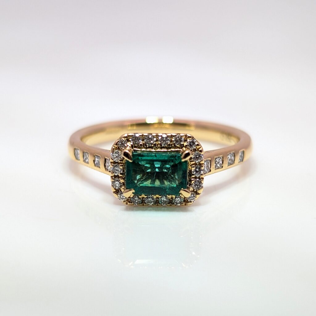 emerald & diamond halo ring with diamond shoulders in 18ct yellow gold