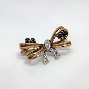 Locally sourced pre-loved vintage and antique jewellery at Aleks Jewellers. Discover our Pre-Loved Sapphire & Diamond Bow Brooch in 9k Yellow Gold.